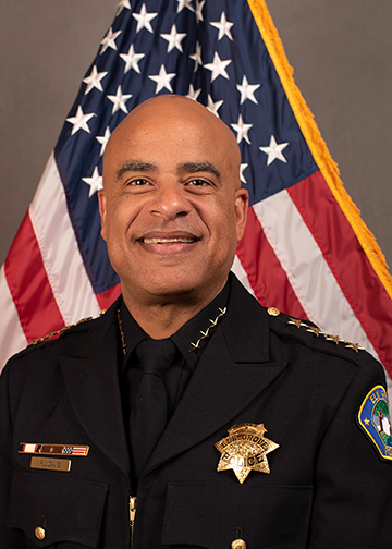 headshot of Bobby Davis, a bald, middle aged Black man smiling in a police uniform