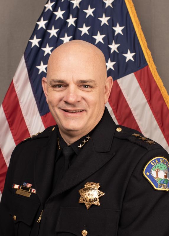 headshot of Brian schopf, a bald, middle aged white man smiling in a police uniform